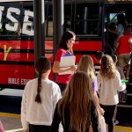 A LifeWise Academy teacher in watches as fifth graders board a bus for their weekly lesson at a nearby church.
