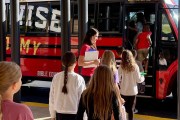 A LifeWise Academy teacher in watches as fifth graders board a bus for their weekly lesson at a nearby church.