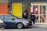 Two Immigration and Customs Enforcement officers detain a woman outside a day care in Chicago’s Roscoe Village neighborhood, pressing her against a car as another officer moves toward the building entrance.