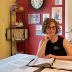 Erin Moulton sits at a table surrounded by archival papers and research.