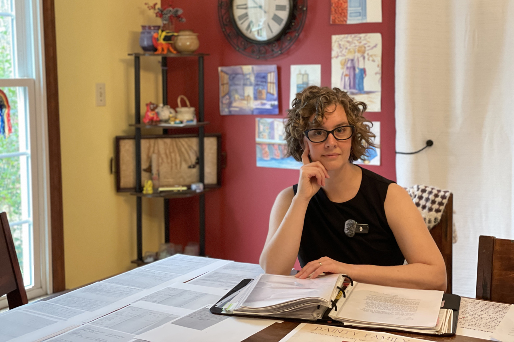 Erin Moulton sits at a table surrounded by archival papers and research.