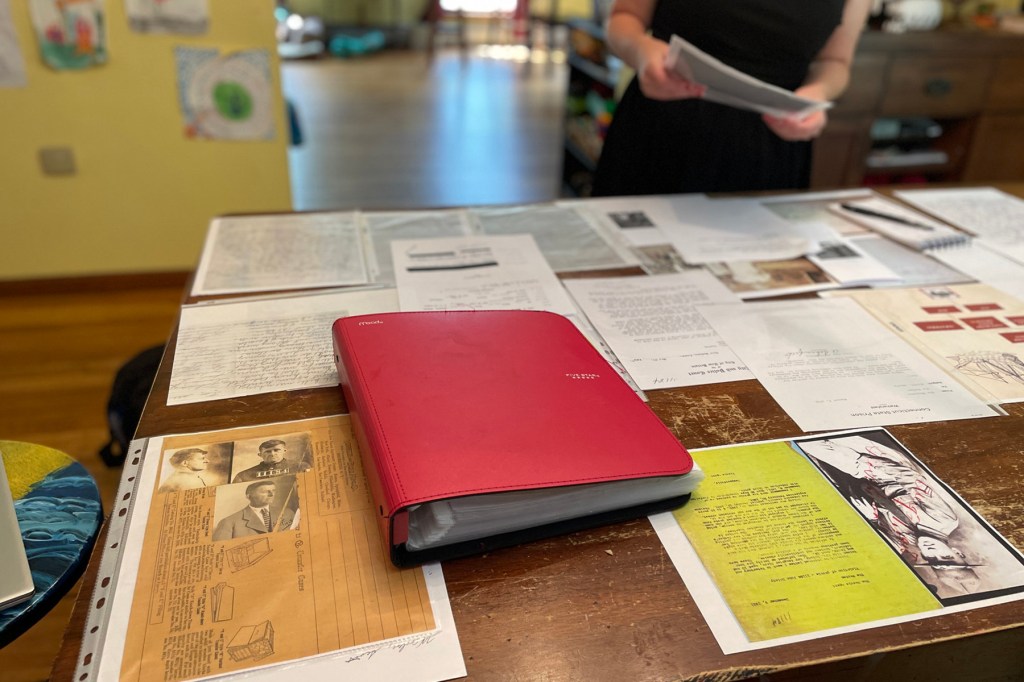 A table full of papers and a red binder.