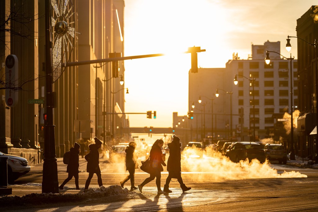 People cross Michigan Avenue in Downtown Detroit in the evening.