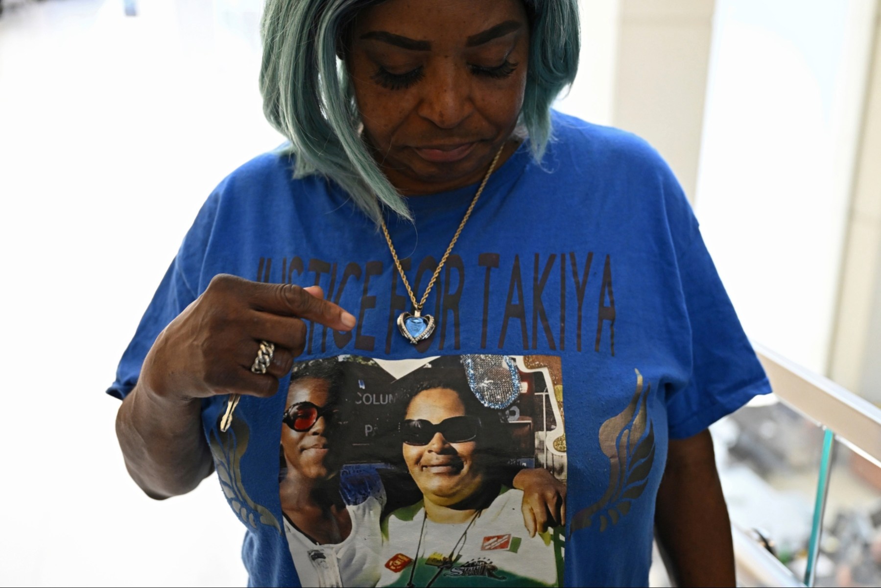 Nadine Young, grandmother of Ta'Kiya Young, shows her shirt to reporters.