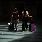 Two women with suitcases walk through an airport.