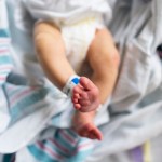 A newborn photographed from overhead in a hospital bassinet.