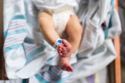 A newborn photographed from overhead in a hospital bassinet.