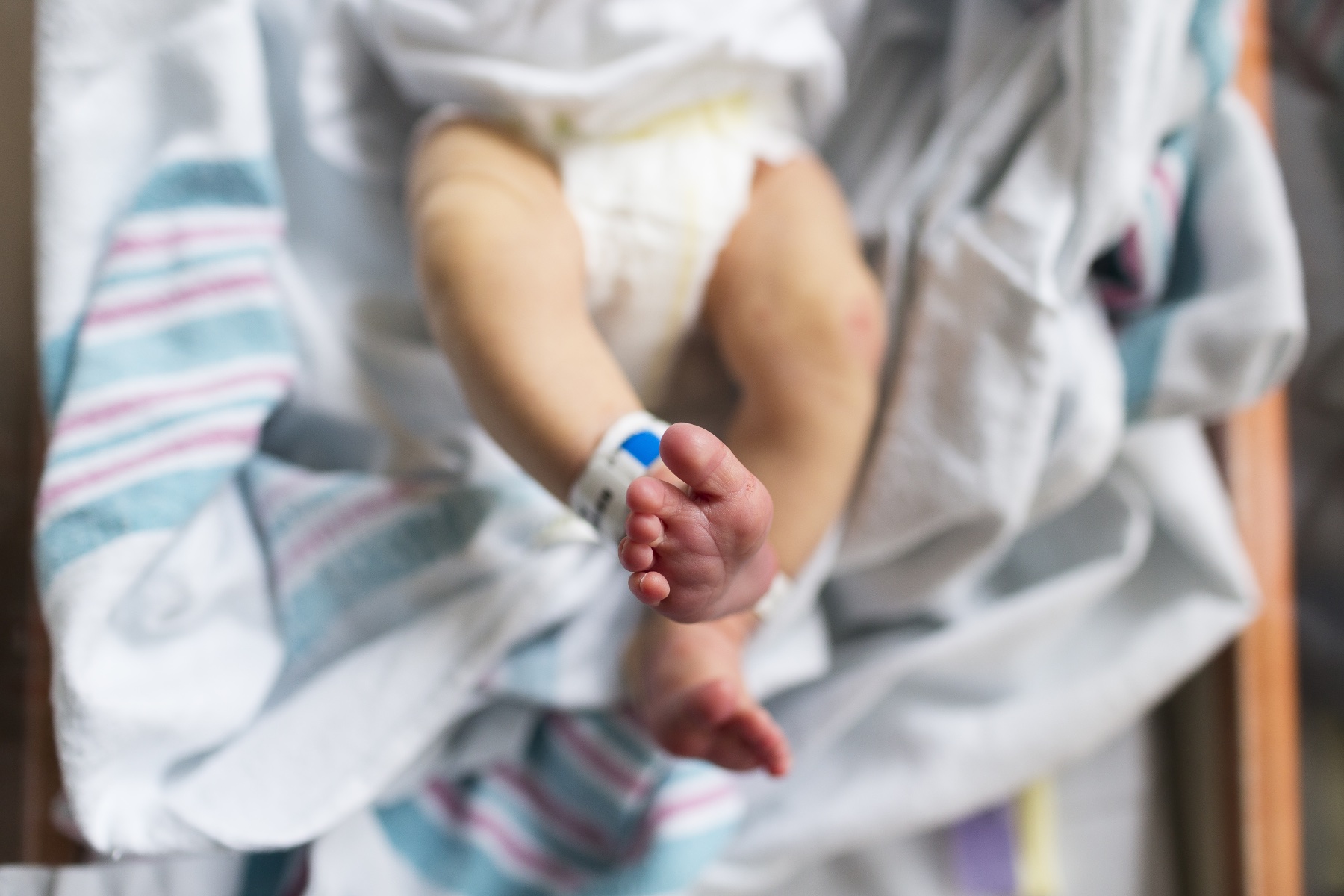 A newborn photographed from overhead in a hospital bassinet.