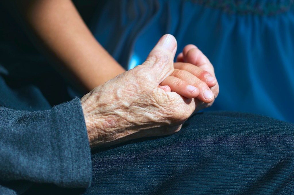 A wrinkled hand holding a child's hand.