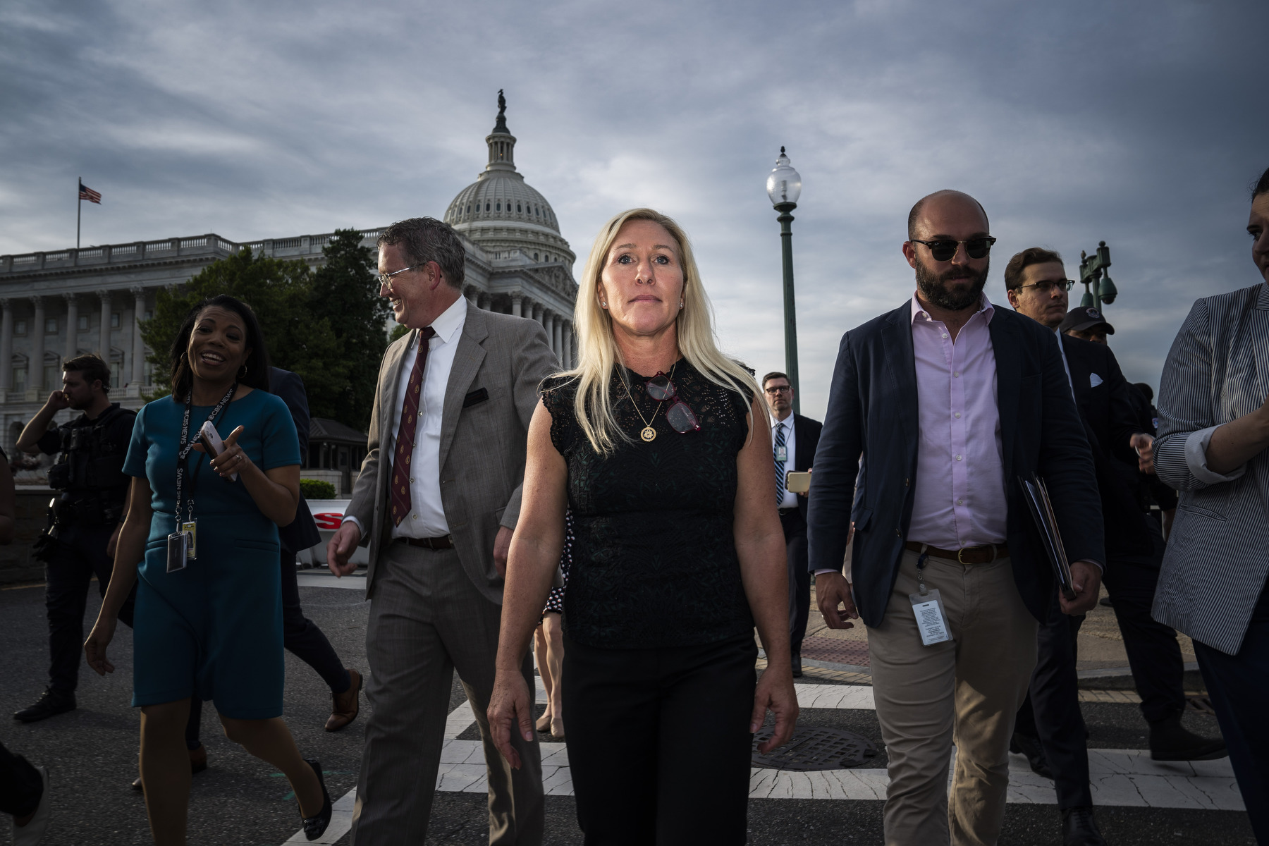 Greene walks away from the Capitol, crossing a street surrounded by others.