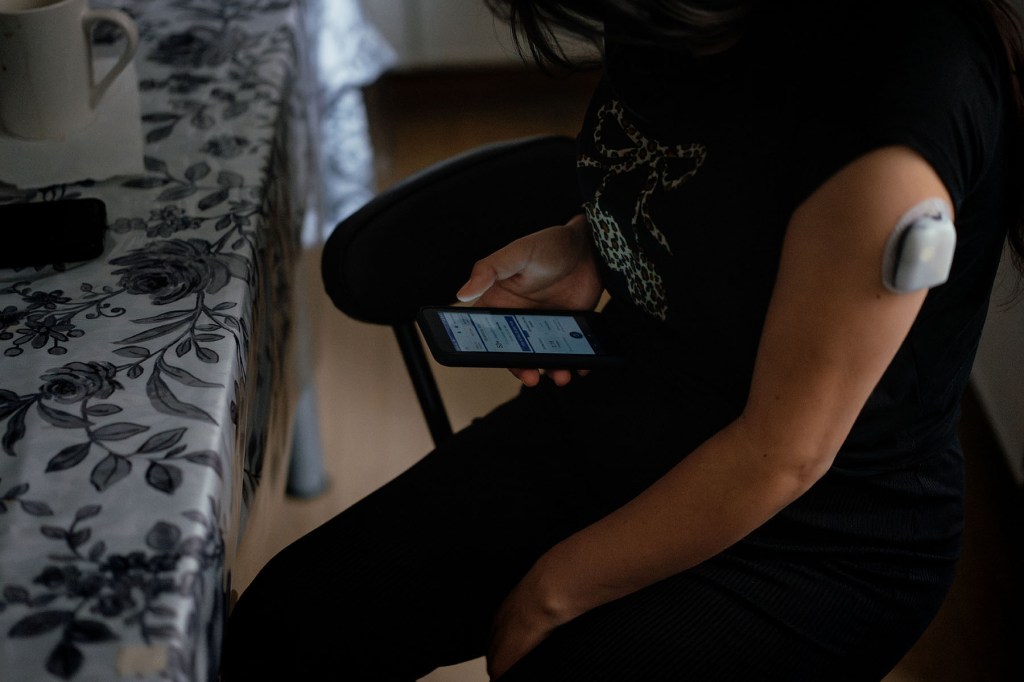 A close-up of an arm with a continuous glucose monitor attached.