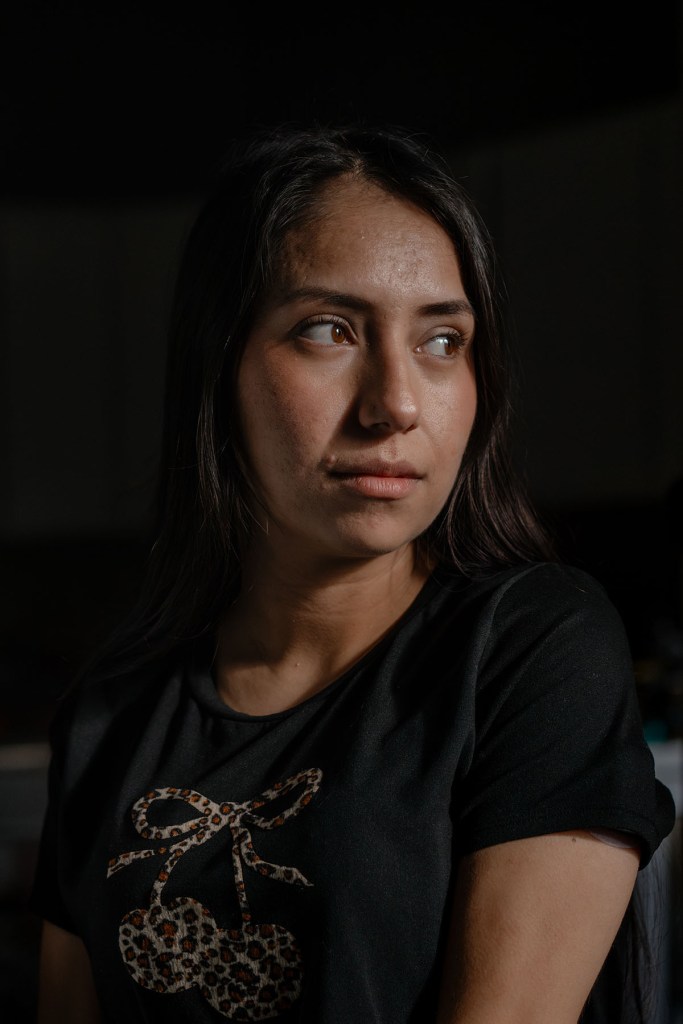 A close-up portrait of Nayra Guzmán looking to the side indoors.