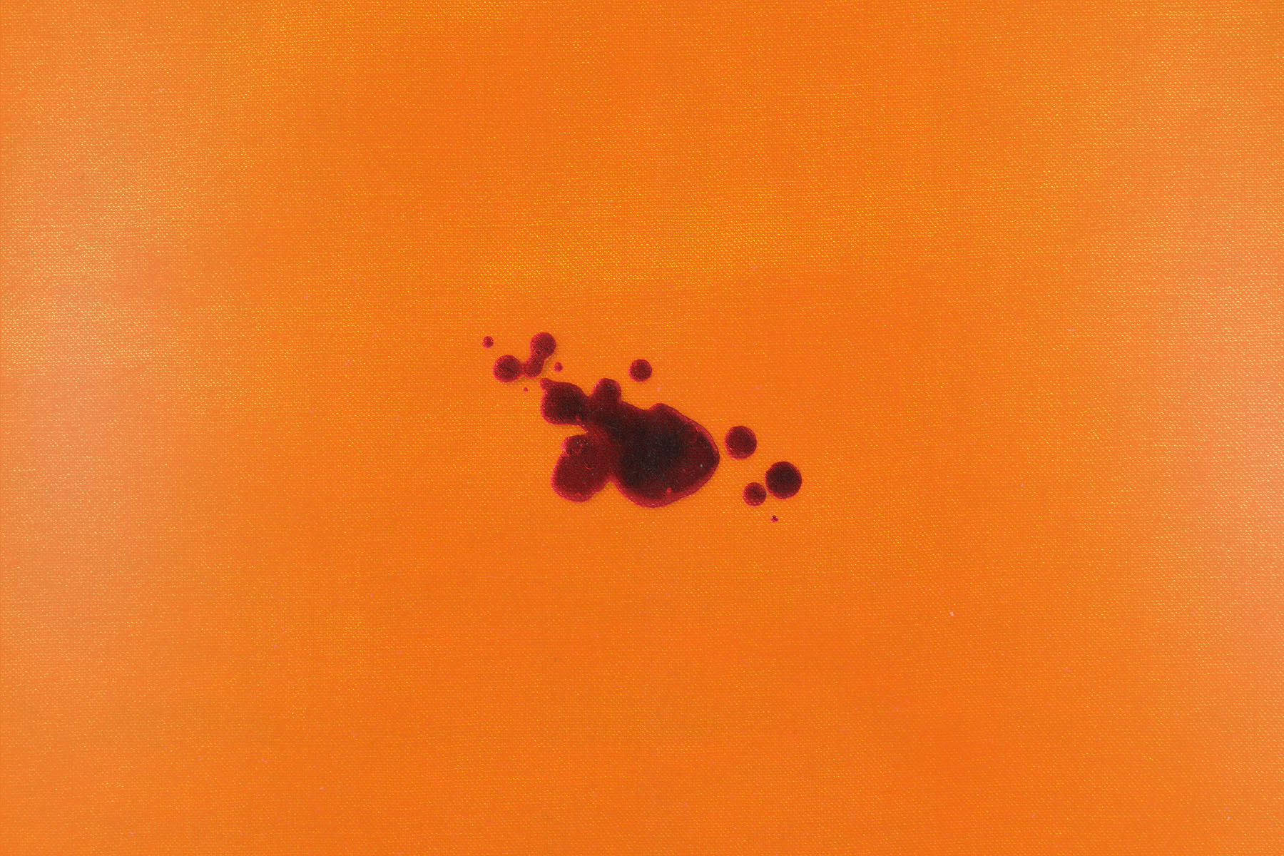 A few dark red drops of blood scattered across a bright orange textile.