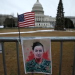A flag and a poster showing Babbitt's military portrait is taped to a fence outside the Capitol.