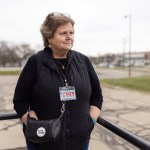 A woman stands outside with her hands in her pockets.