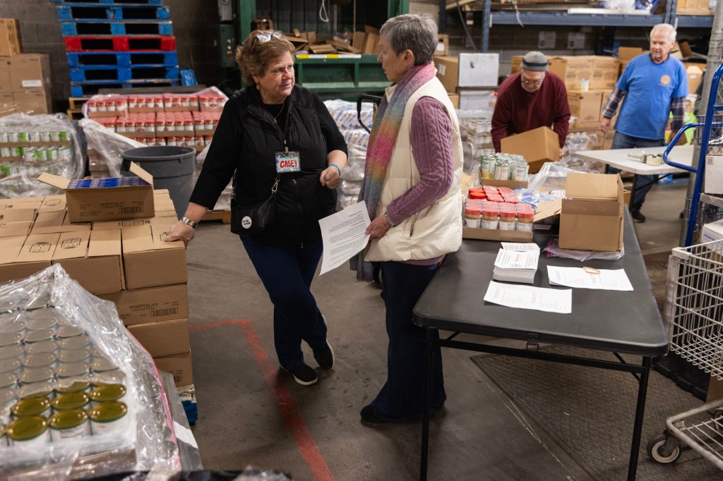 Several people stand around in a grocery back room.