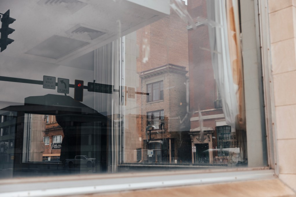 A cityscape is reflected in a downtown window.