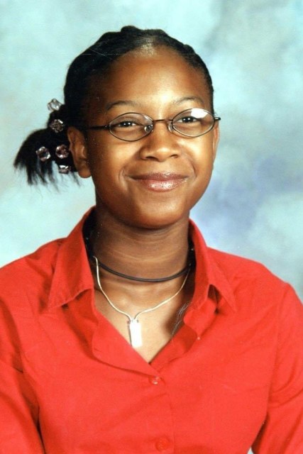 A young girl smiles at the camera in a school photo.
