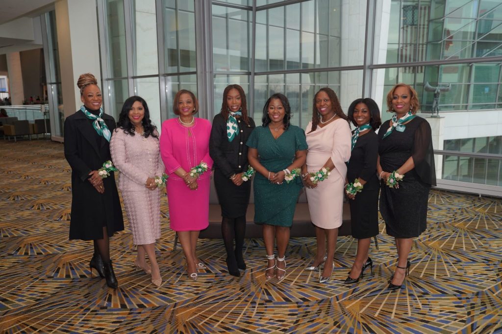 Eight Black women stand together in a line smiling at the camera