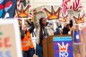 Nekima Levy Armstrong speaks at a podium with a raised fist as thousands rally for the nationwide No Kings day of protest against the Trump administration.