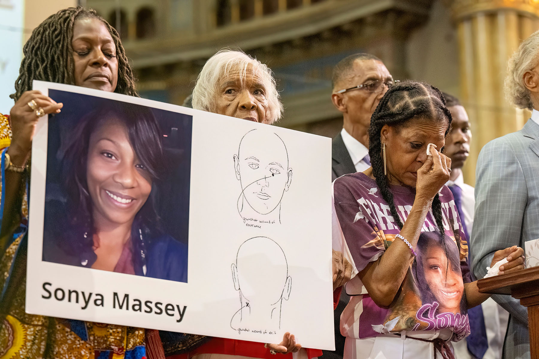 Donna Massey wipes tears from her face as she listens to Rev. Al Sharpton speak during a press conference over the shooting death of her daughter.