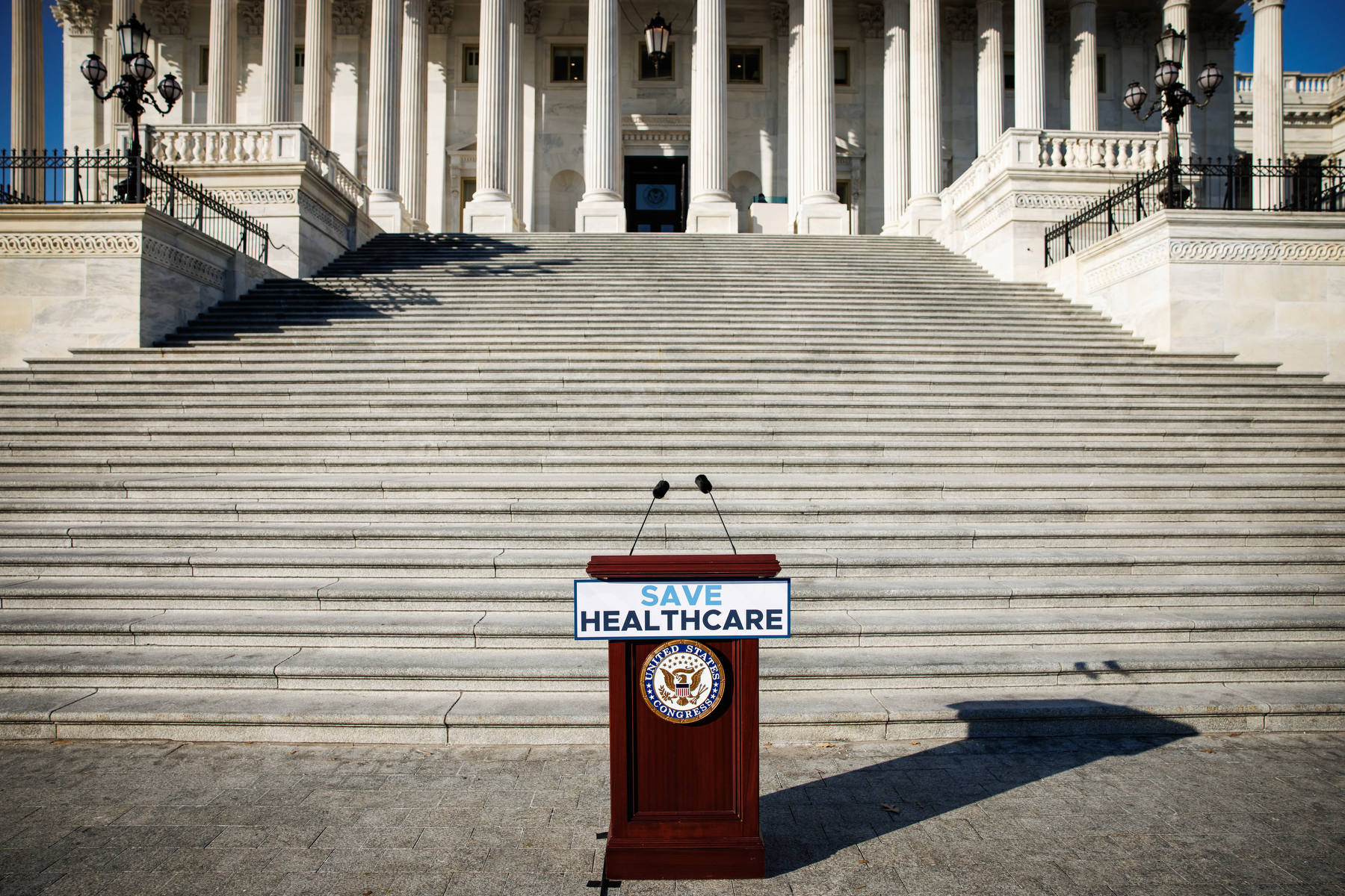 A podium saying save healthcare stands empty at the bottom of stairs.
