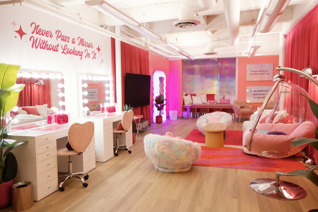 A brightly colored pink room features vanity mirrors, plush seating, rugs and decorative lighting.