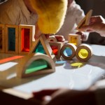 Children play with colorful wooden building blocks on a table.