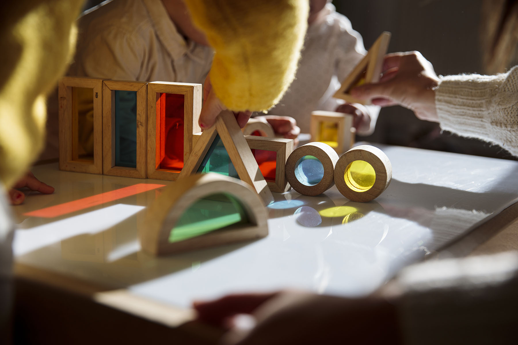 Children play with colorful wooden building blocks on a table.