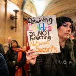 A woman holds a sign denouncing the detention of children by ICE.