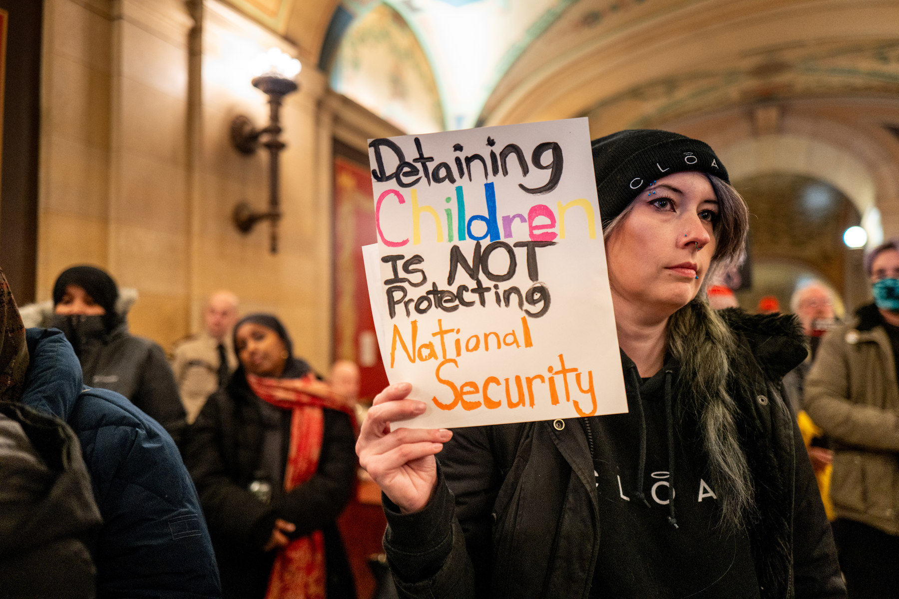 A woman holds a sign denouncing the detention of children by ICE.