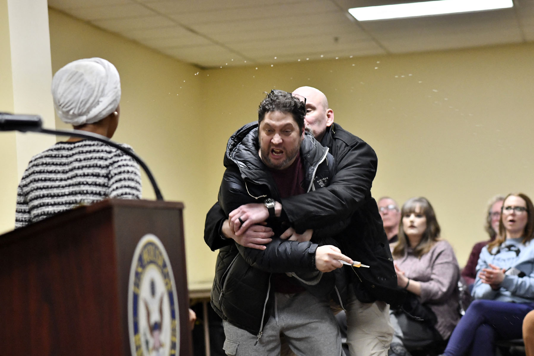 A man is tackled after spraying an unknown substance at Rep. Ilhan Omar during a town hall.