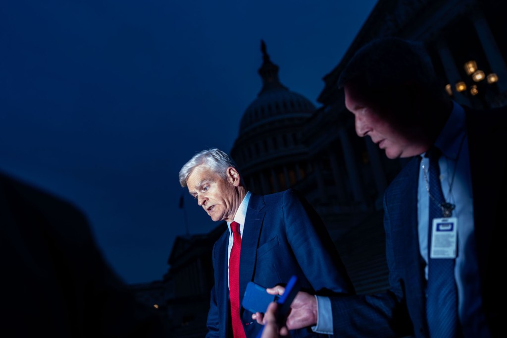 Sen. Bill Cassidy speaks with reporters as he departs the Capitol at night in Washington, D.C.