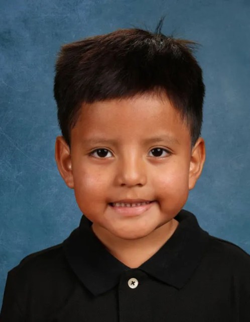 A school portrait of Liam Ramos, a young boy with short dark hair, wearing a black collared shirt against a blue studio background.