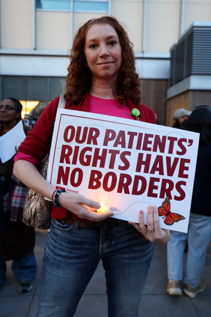 A woman holds a sign saying our patients rights have no borders.
