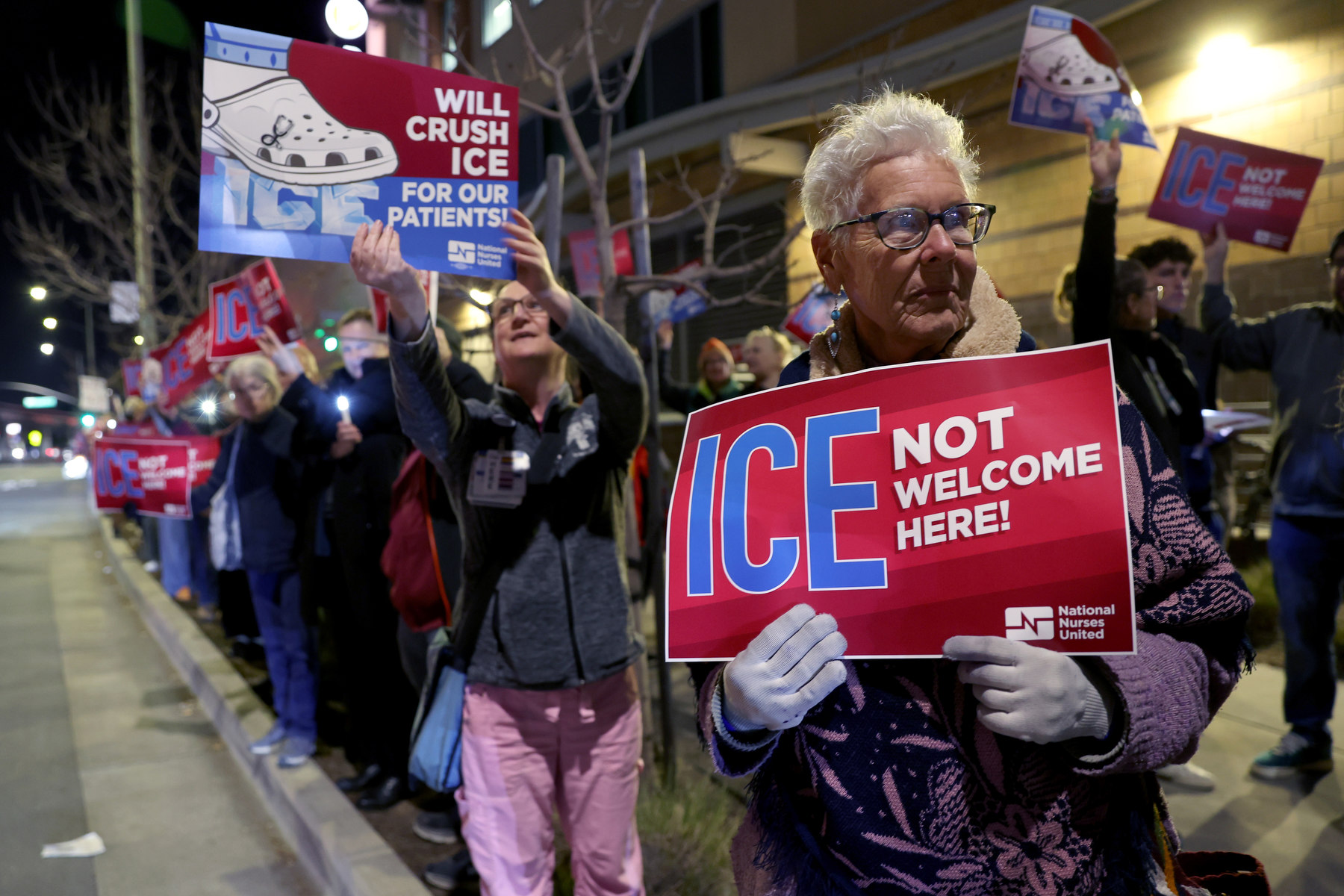 Nurses hold signs at a candlelight vigil and protest.