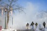 Masked ICE agents walk through tear gas on a street in Minneapolis.