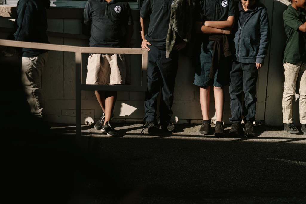 A line of children stand along a wall