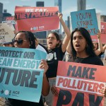 A group of protesters march across the Brooklyn Bridge holding signs that read “Protect Our Clean Energy Future” and “Make Polluters Pay” during a Climate Strike in New York City.