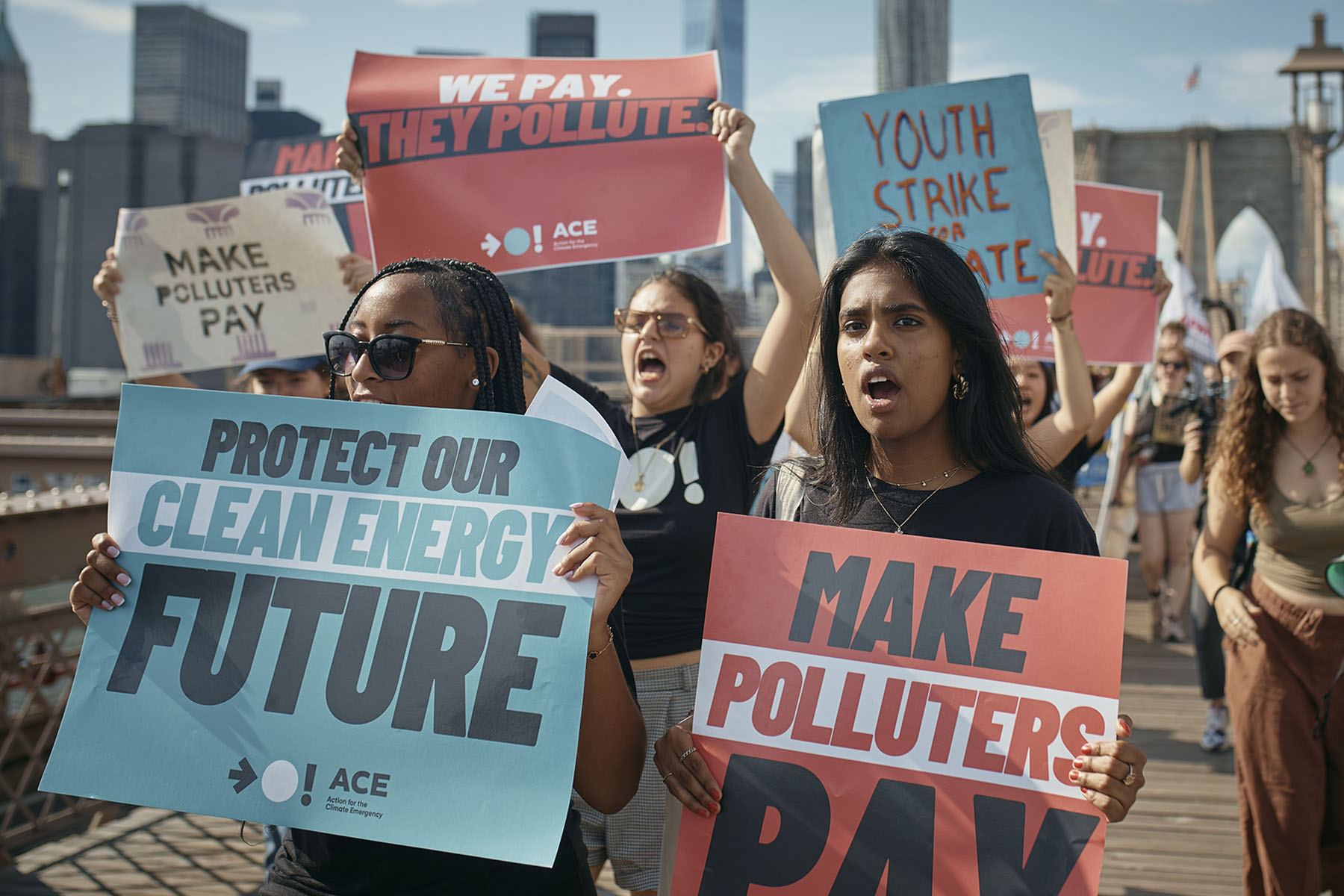 A group of protesters march across the Brooklyn Bridge holding signs that read “Protect Our Clean Energy Future” and “Make Polluters Pay” during a Climate Strike in New York City.