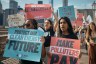 A group of protesters march across the Brooklyn Bridge holding signs that read “Protect Our Clean Energy Future” and “Make Polluters Pay” during a Climate Strike in New York City.