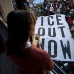 People look on from a skyway as demonstrators march during a protest against ICE enforcement carrying a large banner that reads 