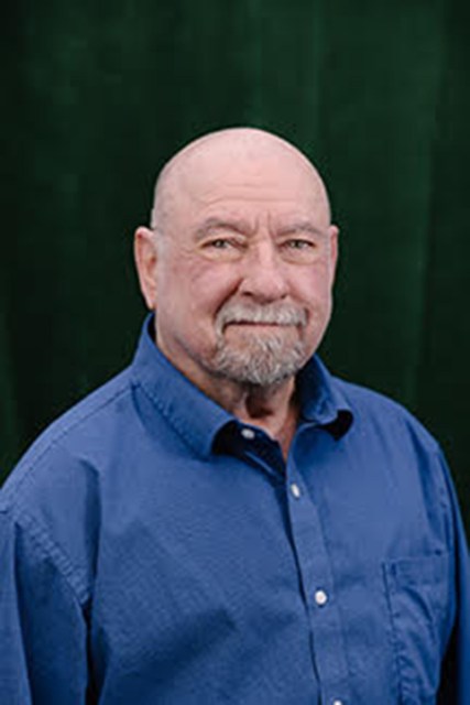 A closeup portrait of Green wearing a blue button-down shirt.