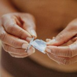 Mid section of woman holding hormone patch in front of belly.