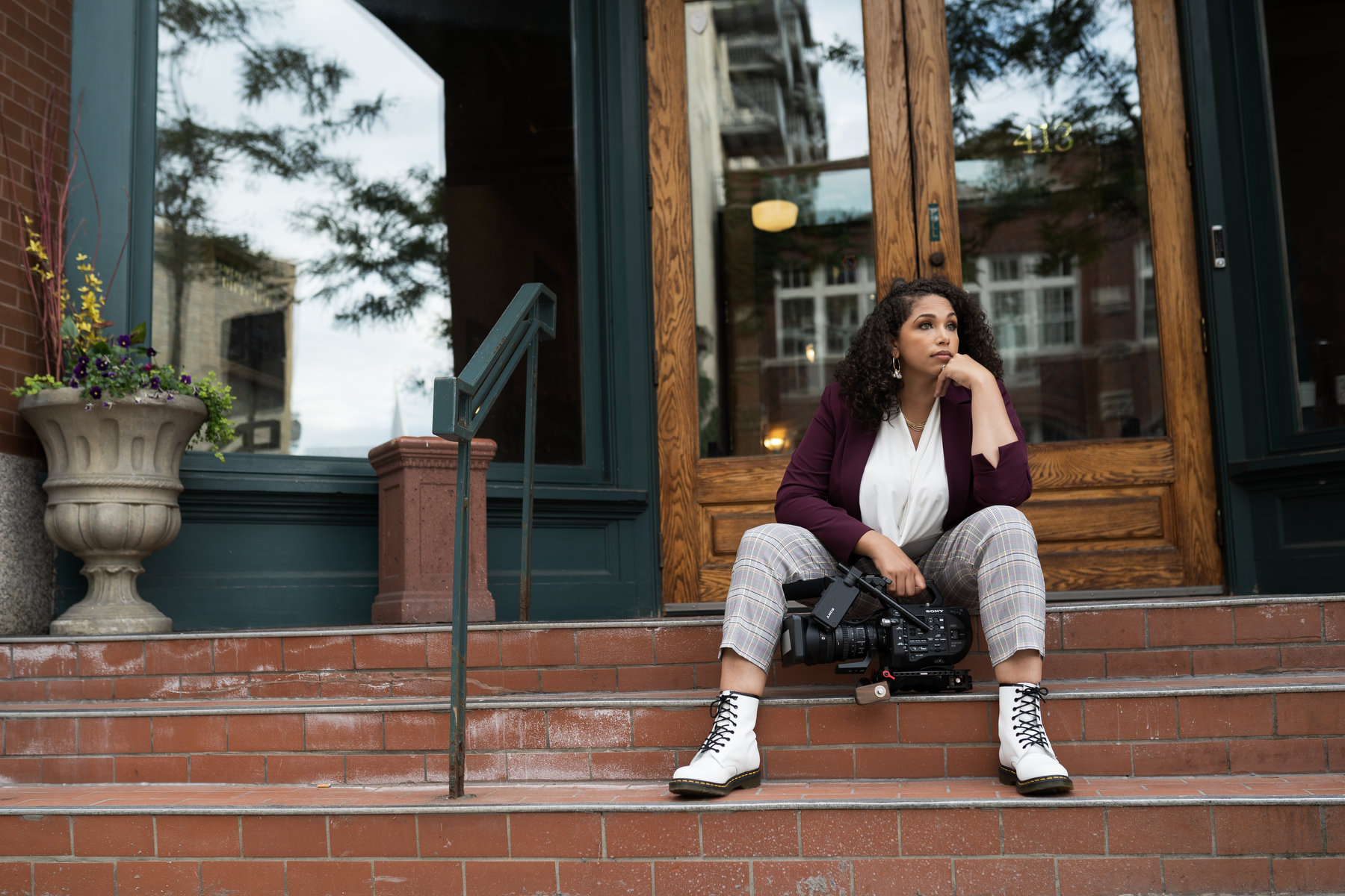 Portrait of Fort sitting on a staircase with a video camera in her hand.