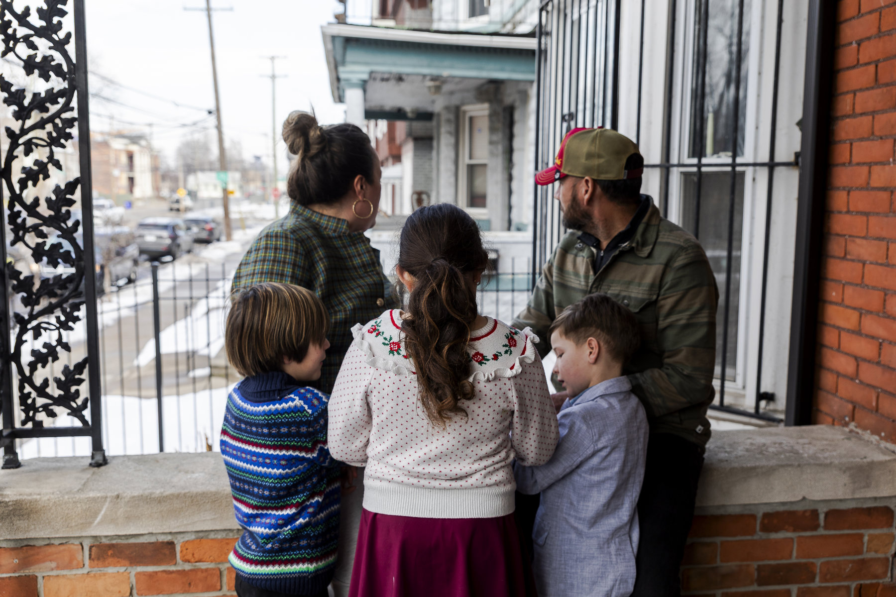 A family of five stand together on a patio facing away from the camera.