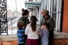 A family of five stand together on a patio facing away from the camera.