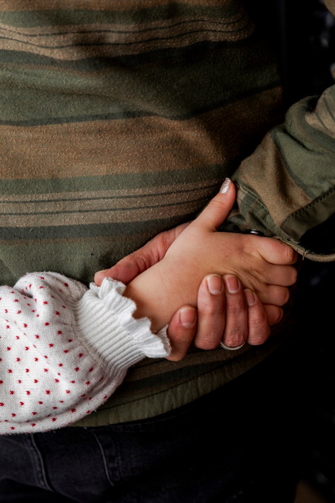 A father clasps his daughter's hand in his.
