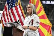 Katie Hobbs, in a Diamondbacks jersey, stands in front of Arizona and U.S. flags.