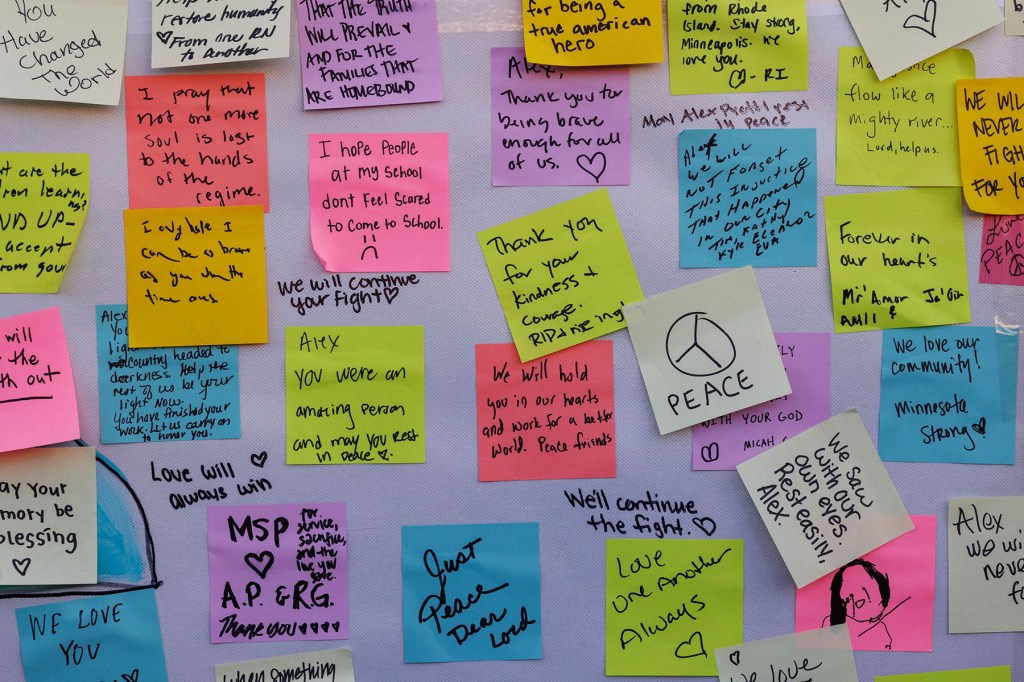 Handwritten notes and messages of grief and solidarity are taped to a wall at a memorial site for Alex Pretti, with colorful sticky notes overlapping one another.